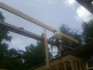 Carpenter setting a ridge beam over a new addition frame — Ice Dam Removal by Roofing Brothers in Searsboro