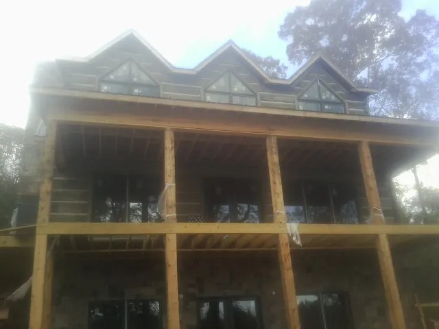 Dormers and porch framing on a large log home under construction — Roof Coating work by our crew in Searsboro