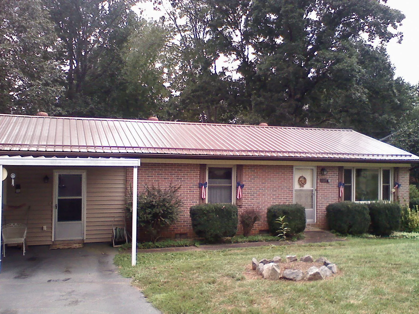 Bronze metal roof and carport on a brick ranch home — Roof Repair work by our crew in Searsboro