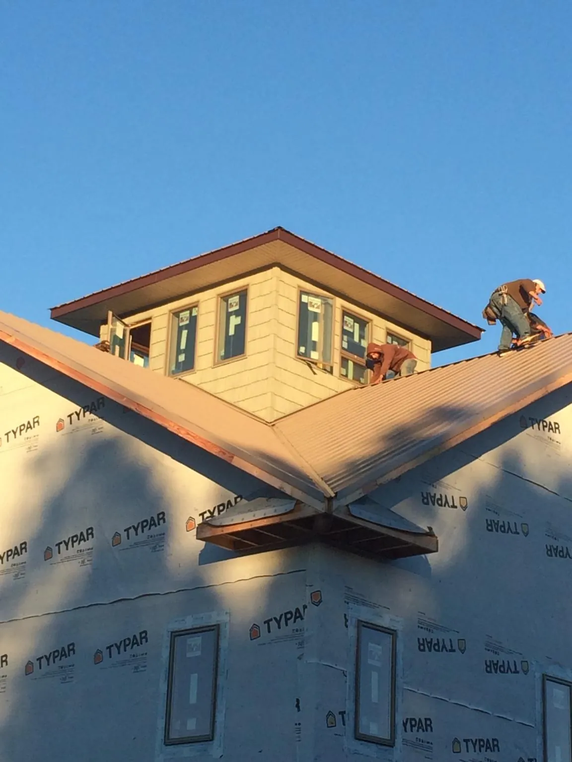 Roofers working around a rooftop cupola on a new metal roof at sunset — Roof Waterproofing in Searsboro by Roofing Brothers